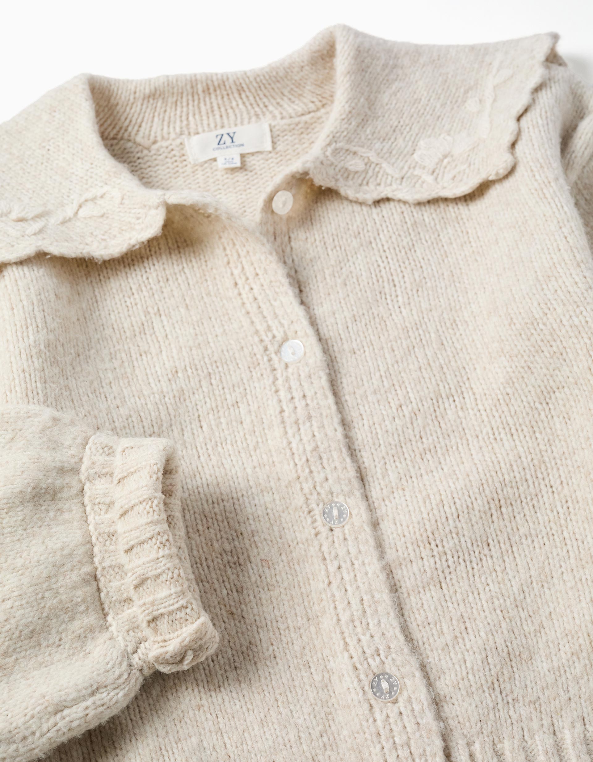 Rebeca niña Zippy Collection punto beige claro crema cuello babero volantes bordados florales hojas botones frontales mangas largas abullonadas puños acanalados bajo acanalado
